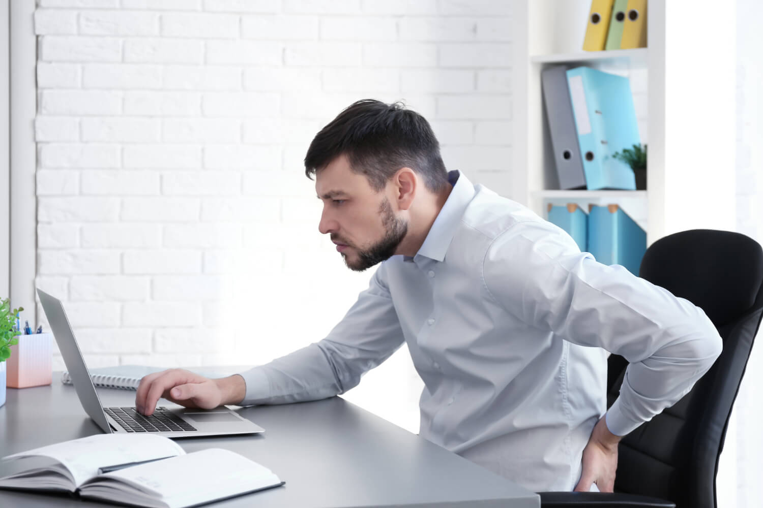 Man with back pain using laptop at desk