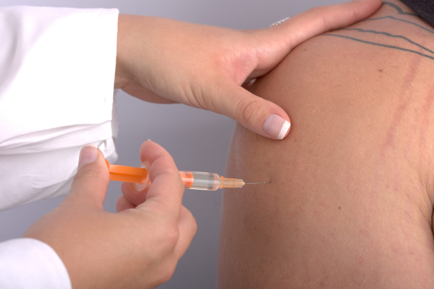 Doctor administering injection in patient's shoulder