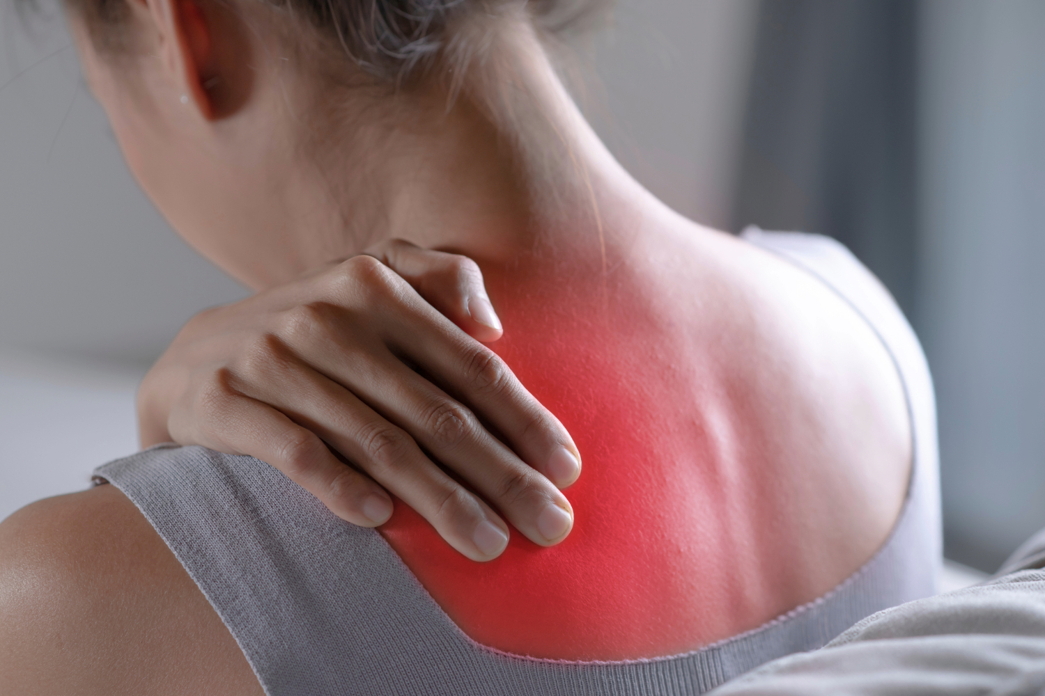 Woman with hand on neck, red patch indicating pain.