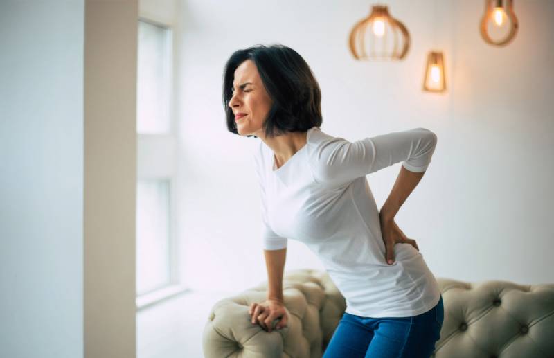 Woman with back pain in living room.