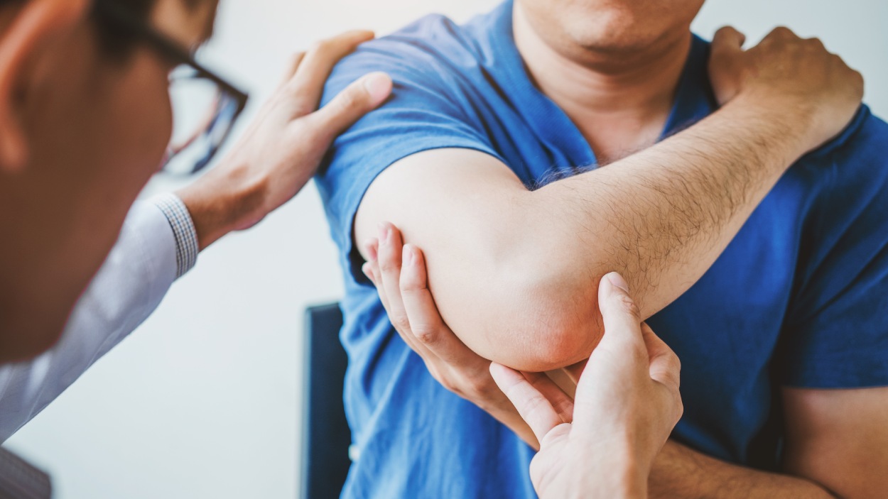Doctor examining man's elbow pain.
