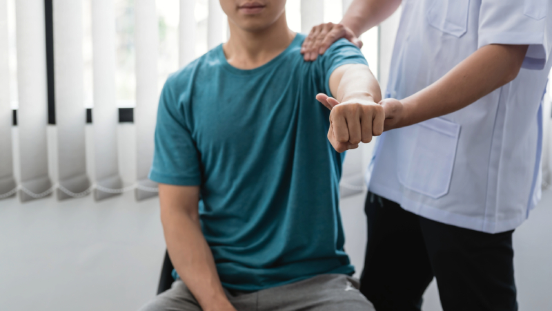 Physical therapist assisting man with arm exercises.
