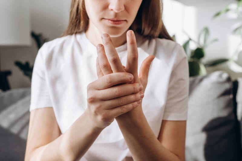 Woman massaging painful finger, Austin, Texas pain relief.