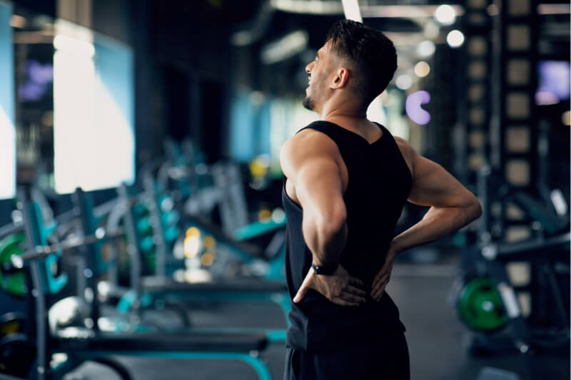 Man in gym holding lower back in pain.