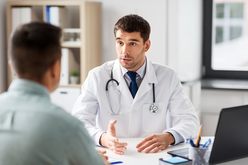Doctor talking to a patient at a desk.