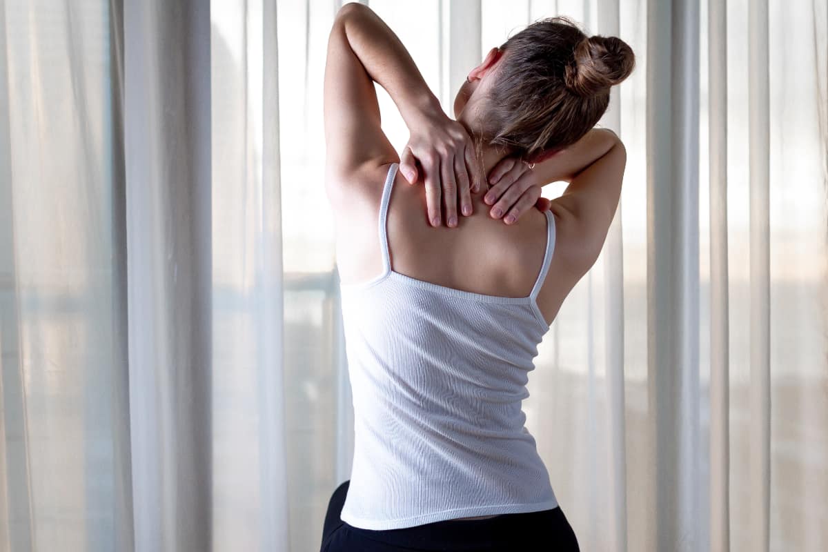 Woman stretching neck against a curtain background.