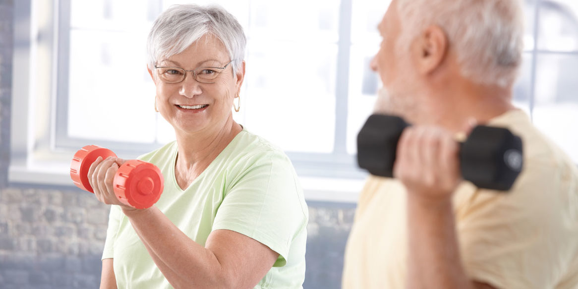 Elderly couple exercising with dumbbells indoors.