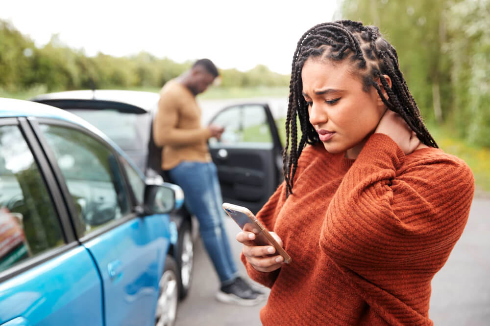 Woman with neck pain at car accident scene.