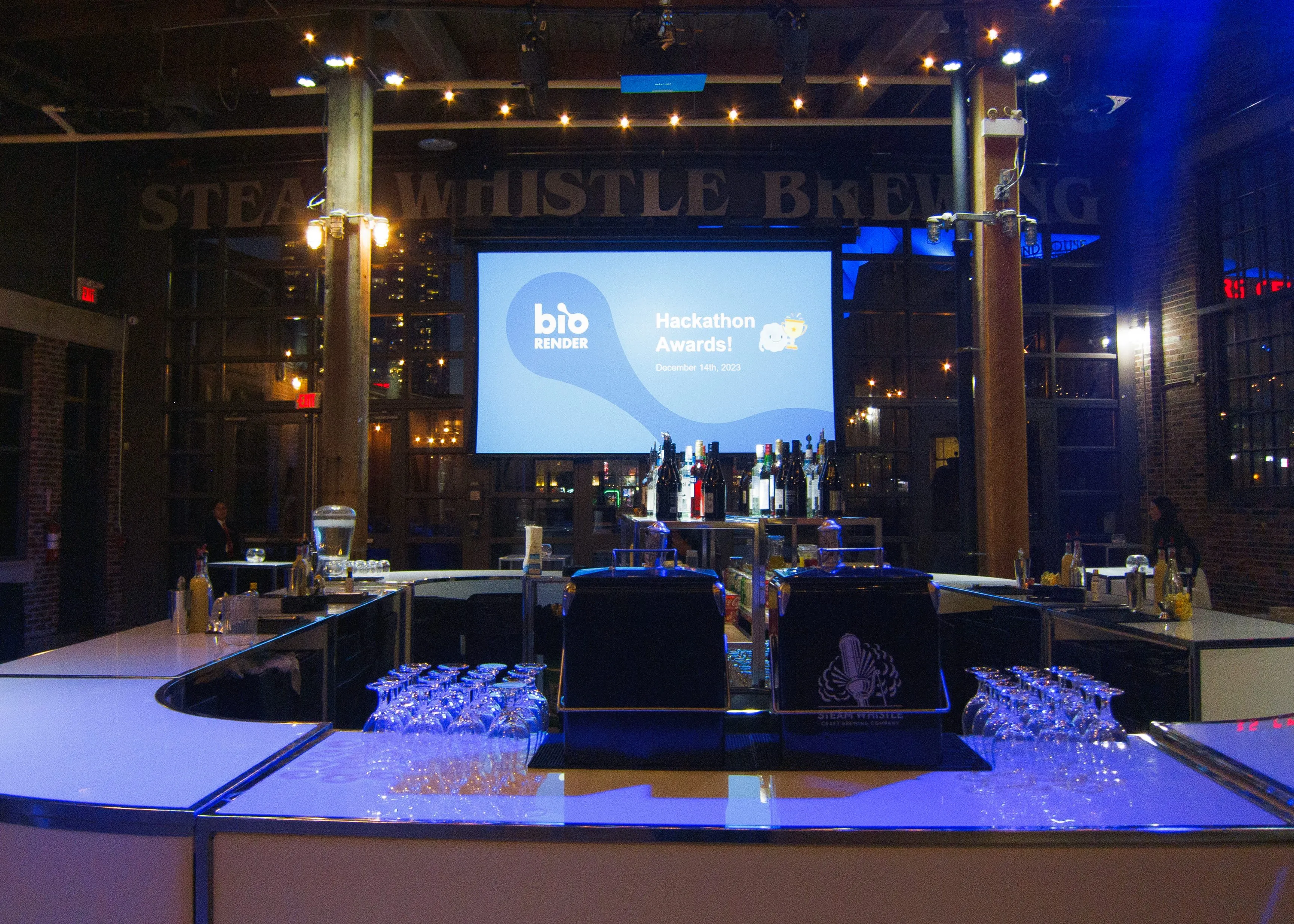 Bar setup at Steam Whistle Brewing with a screen showing BioRender Hackathon Awards, December 14, 2023.