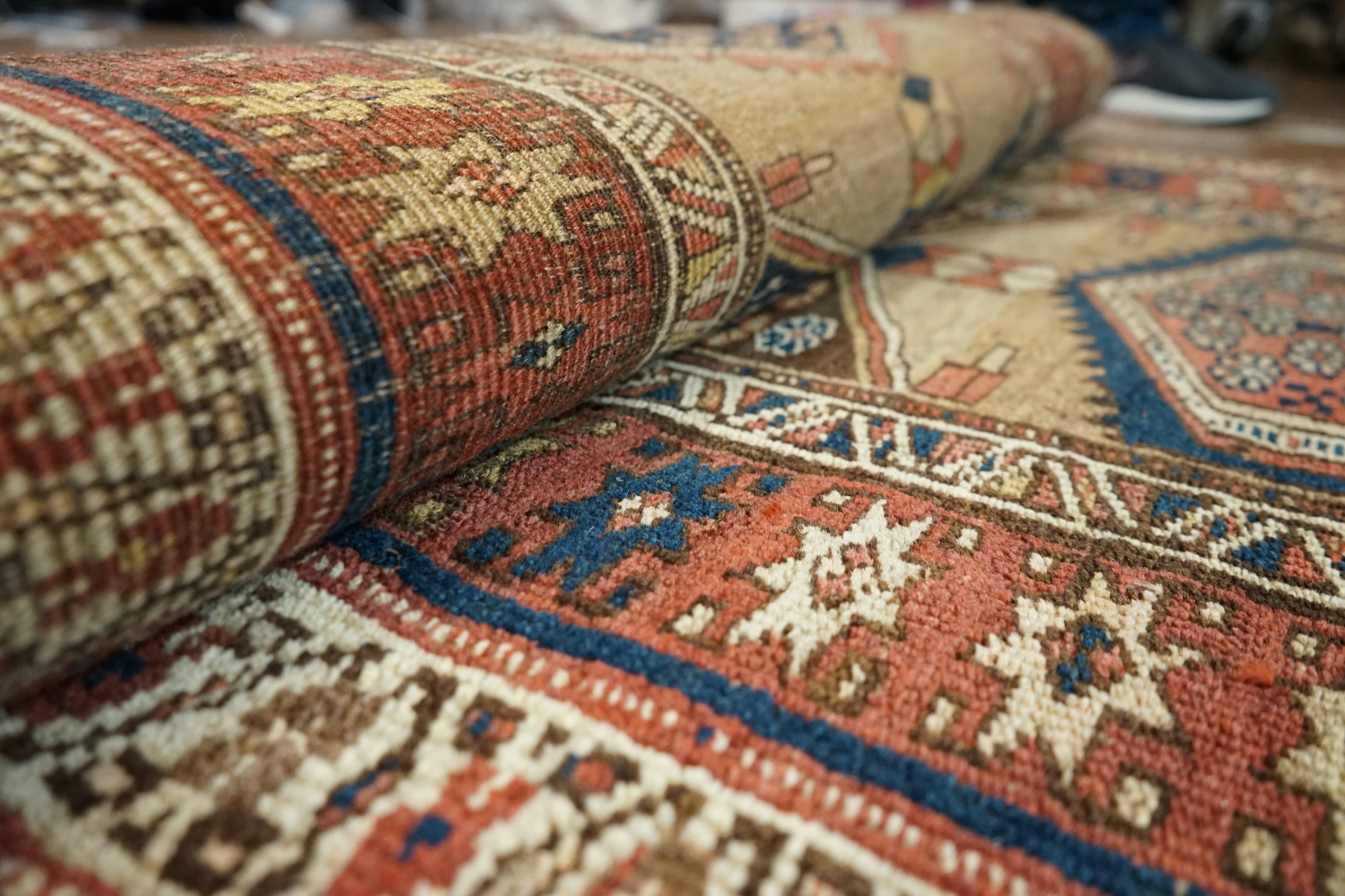 Area rug folder and ready for cleaning; features beige, blue, red, and yellow colours