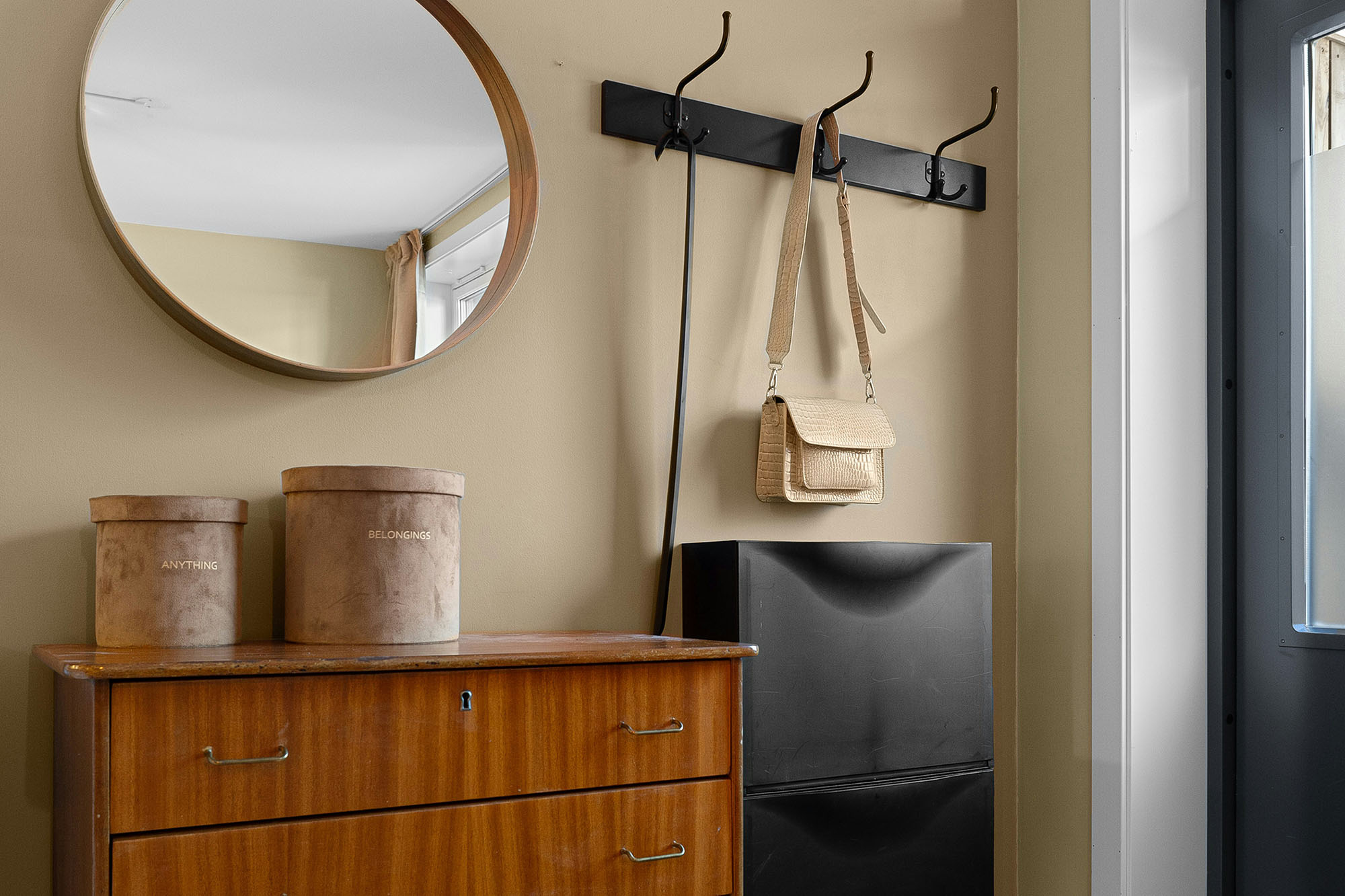 Interior of home entryway with coat rack, shoe storage, dresser, mirror, and buckets for random miscellaneous items.