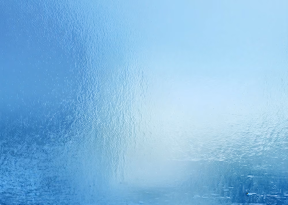 Close-up of textured frosted glass with soft blue hues and light reflections.