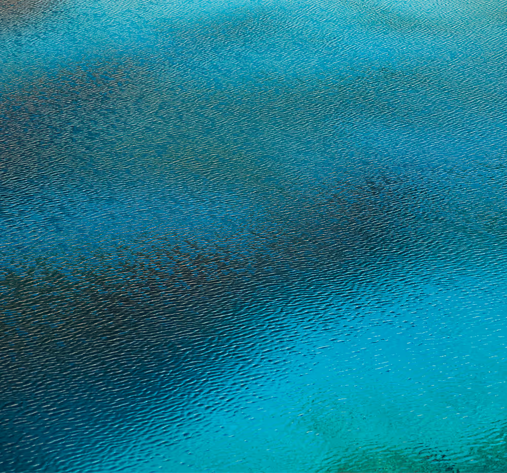 Close-up of rippled turquoise water with darker underwater patches.