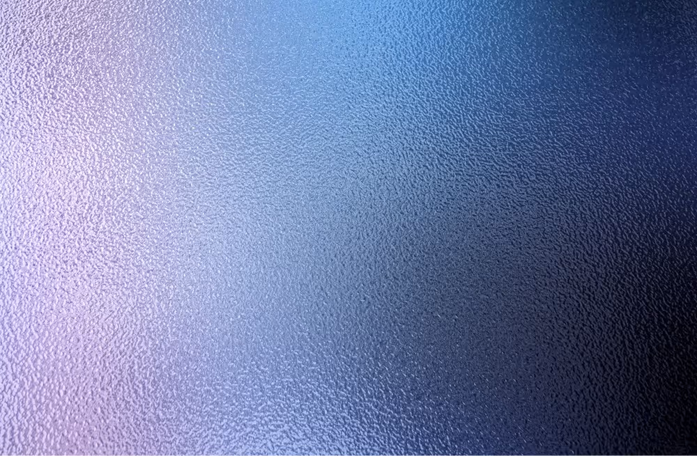 Close-up of textured glass with a gradient of light purple to dark blue colors.