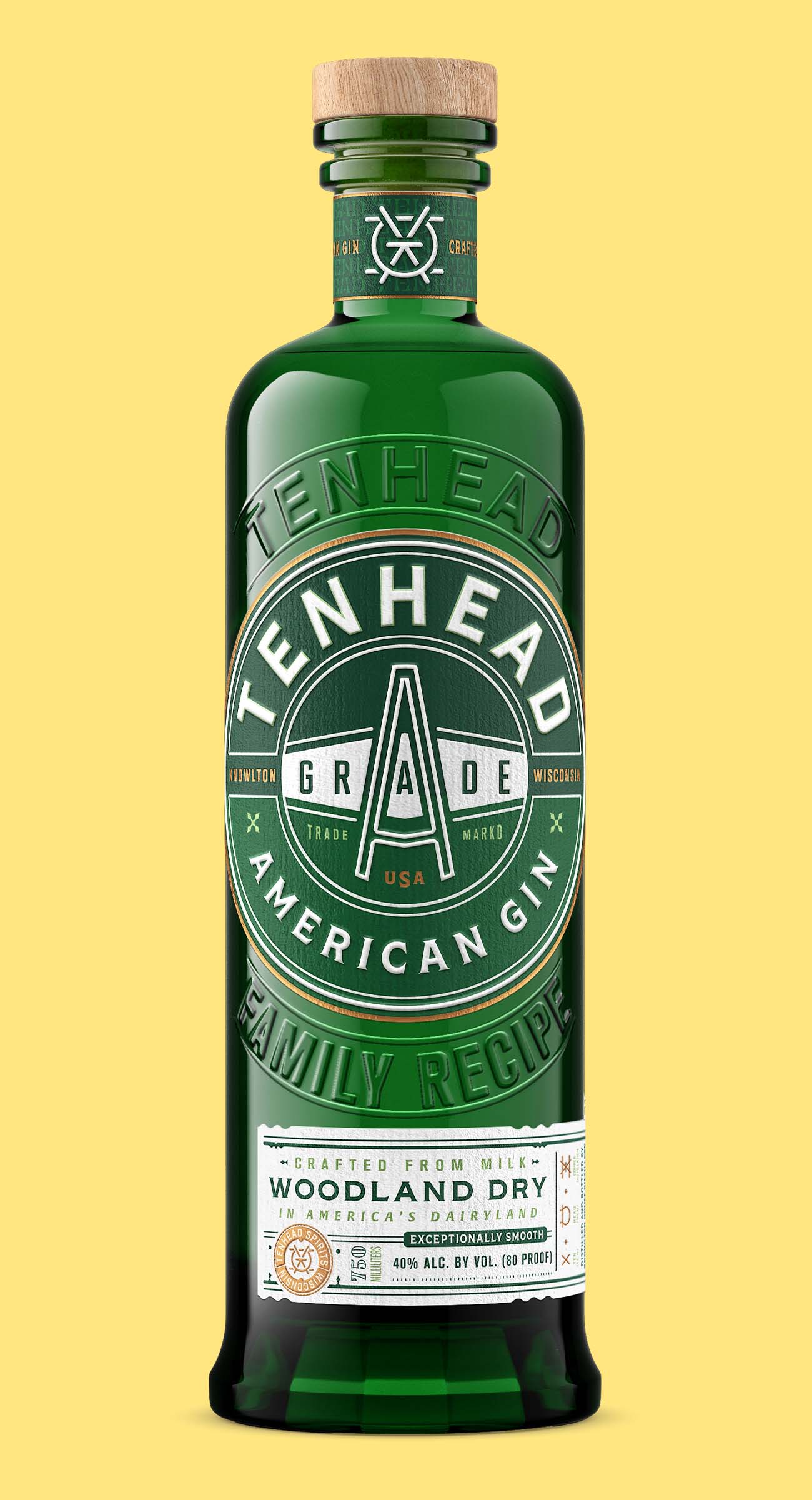 Green glass bottle of botanical gin with embossed details and illustrated white label, shown on a yellow background