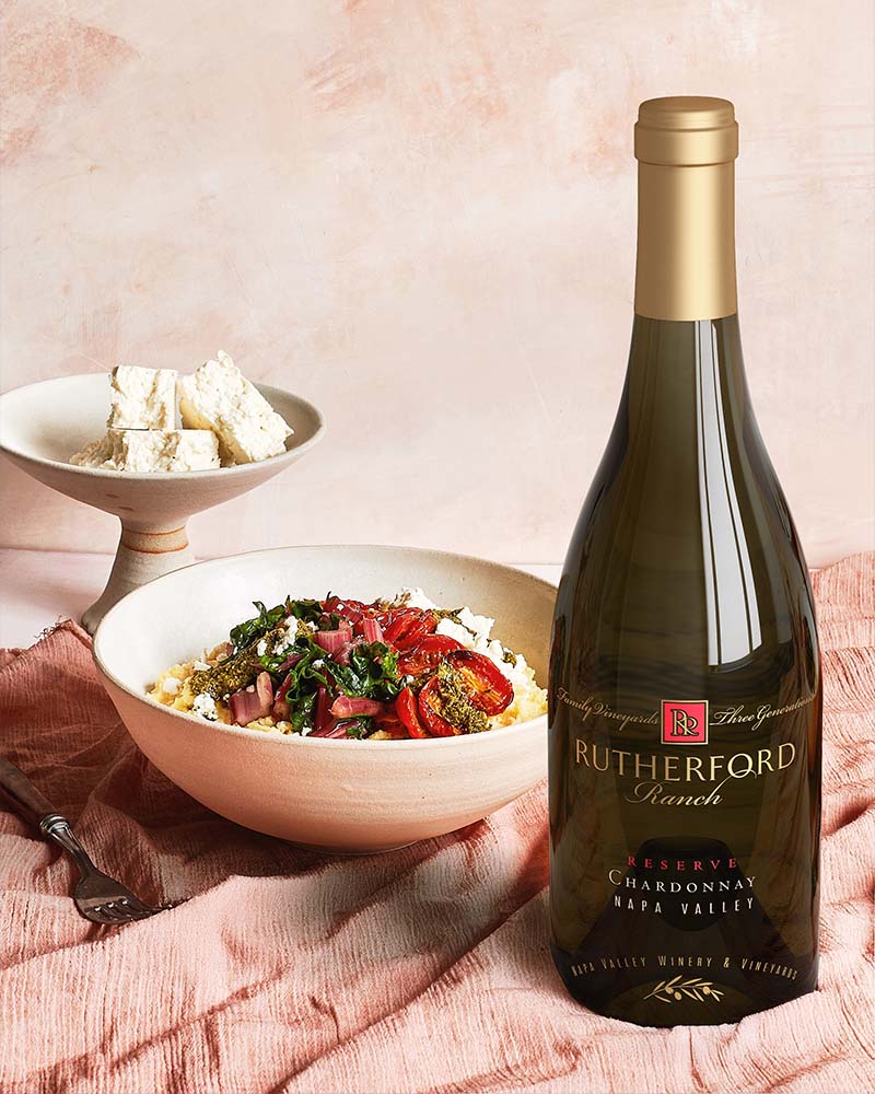 bottle of Napa reserve chardonnay on pink tablecloth next to cherry tomatoes with feta