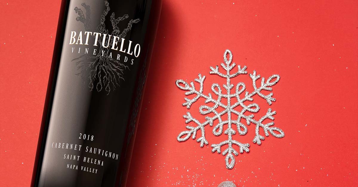 Battuello Vineyards Cabernet Sauvignon bottle styled on red background with glitter snowflake holiday ornament.