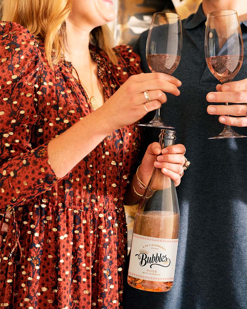 people having fun holding champagne glasses with with a bottle of sparkling rose in hand