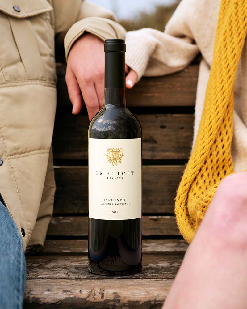 wine bottle between a man and a woman on a bench outdoor