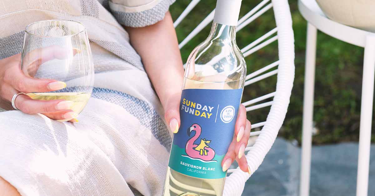 woman holding a bottle of white wine in her hand while outdoor