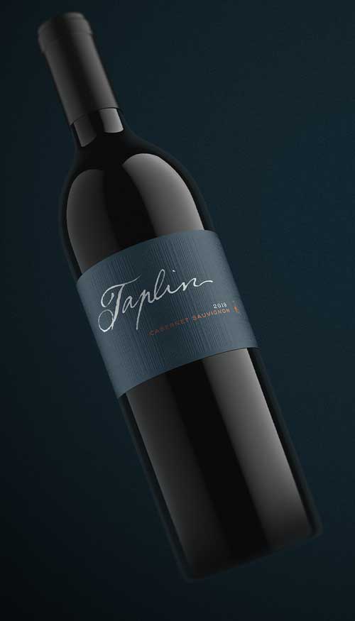 Taplin Cabernet Sauvignon 2019 bottle shot, slate blue wrap label with white script logo on a deep navy backdrop, by Outshinery
