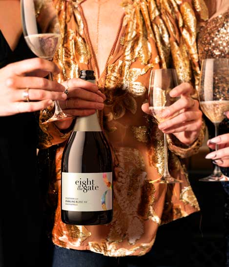 Eight at the Gate Wrattonbully Sparkling Blanc NV bottle held at a celebration with raised glasses, by Outshinery