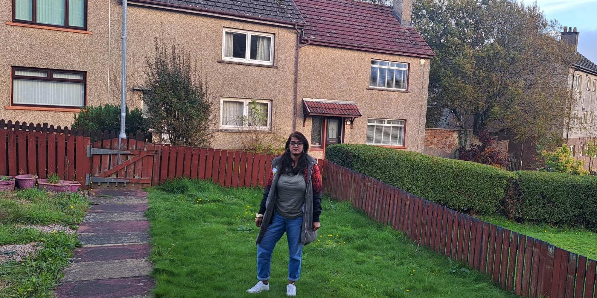 lady in a back garden standing on grass with a house in background