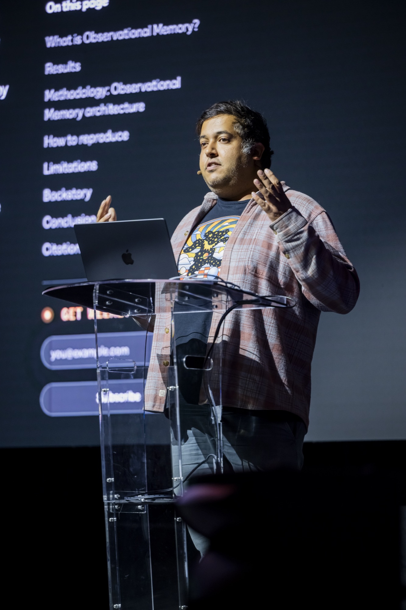 Abhi Aiyer on stage at Agent Night with the observational memory research page projected behind him.