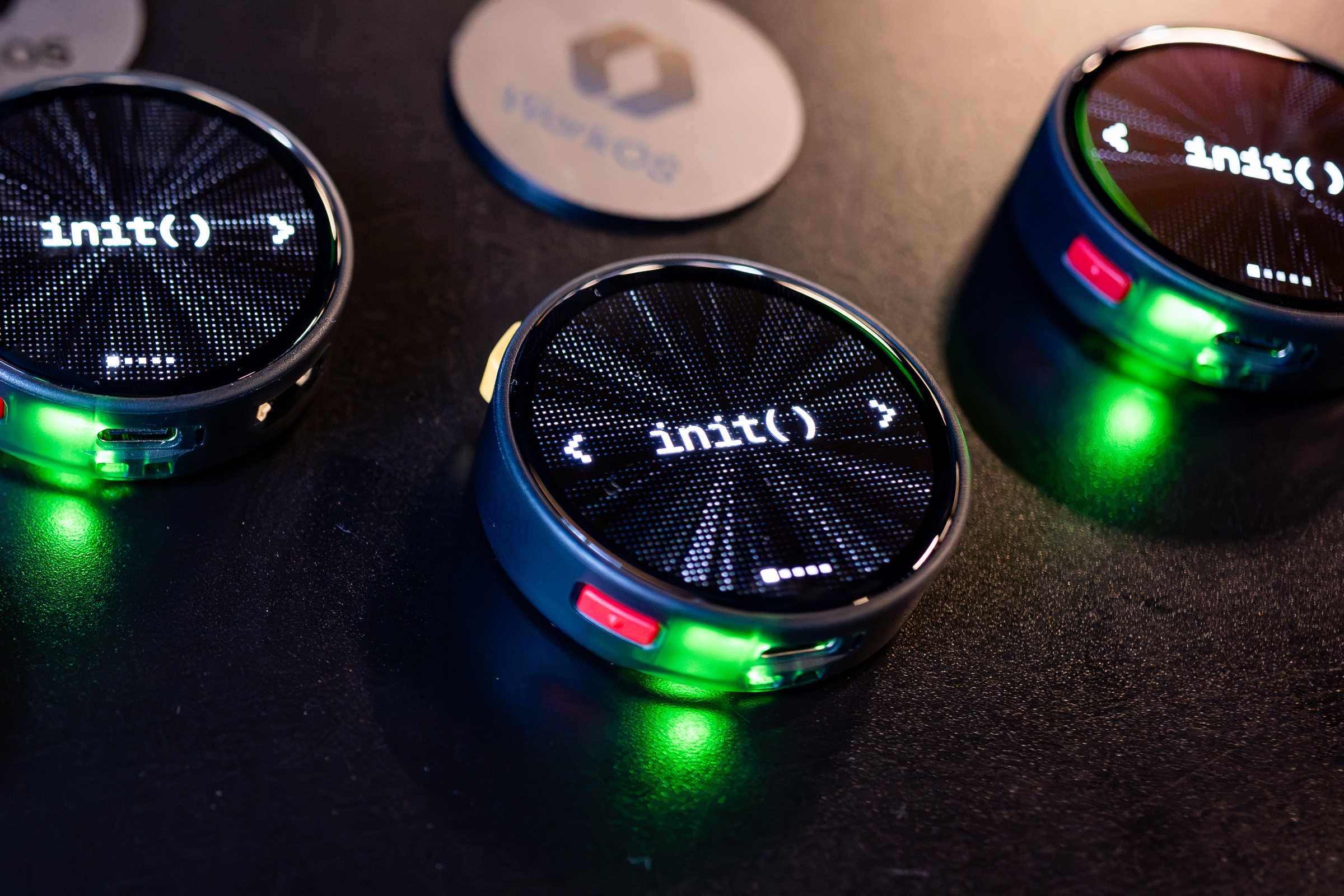 Three init() conference badges displaying the event logo on their round screens.