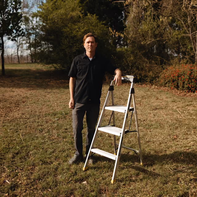 Man standing in a field with a step ladder