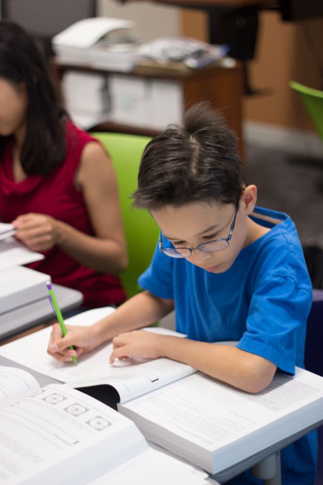 boy-in-blue-shirt-writing-in-book