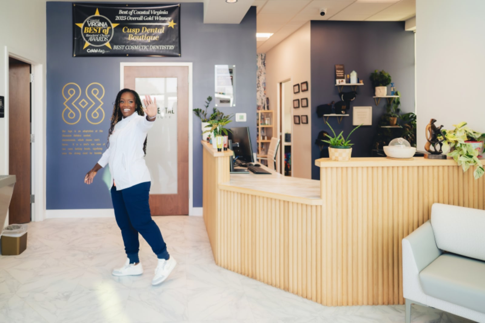 Woman walking through modern dental office reception area with light wood desk and contemporary decor.