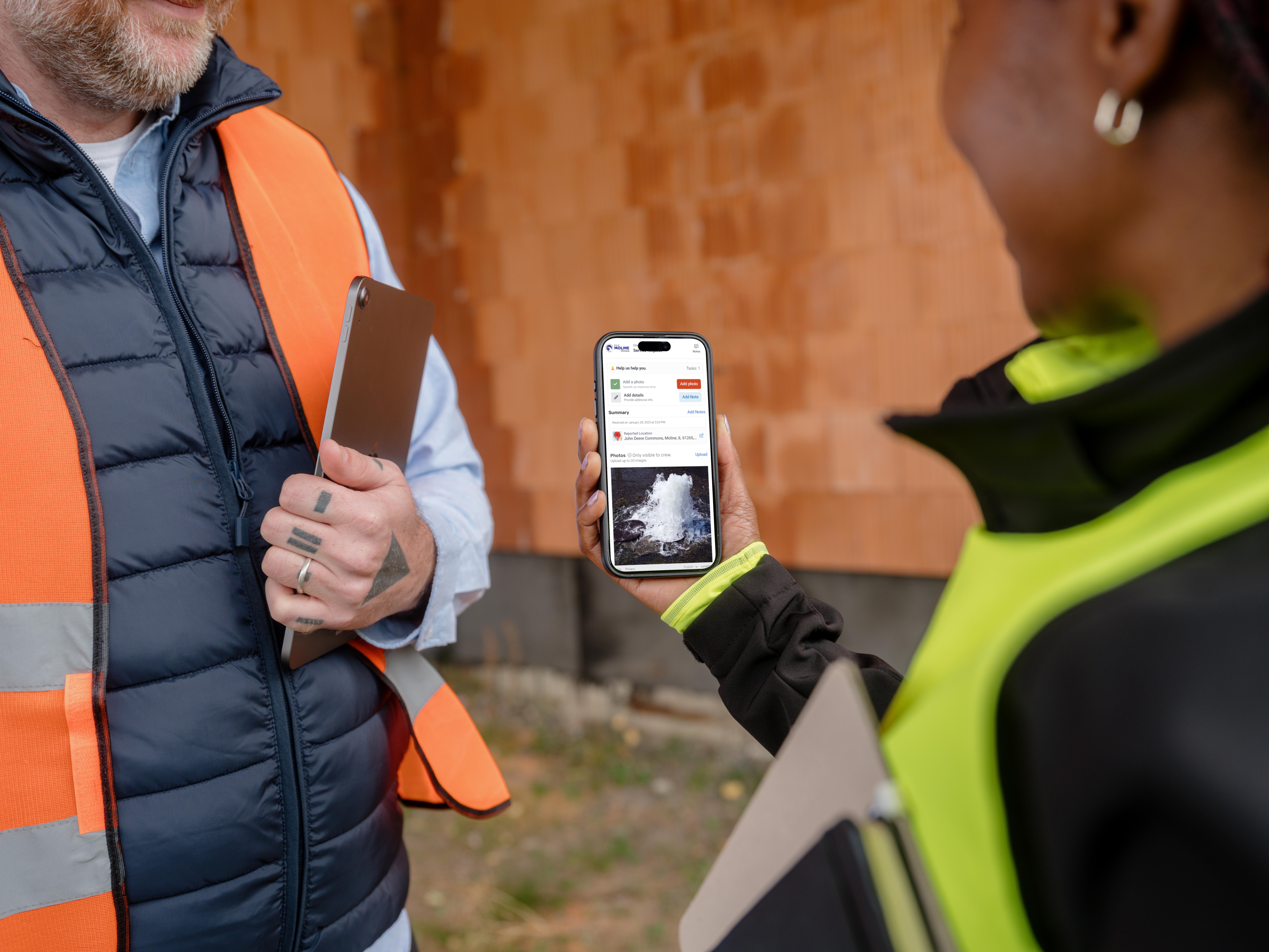 Two public works workers looking at an incident on a cell phone