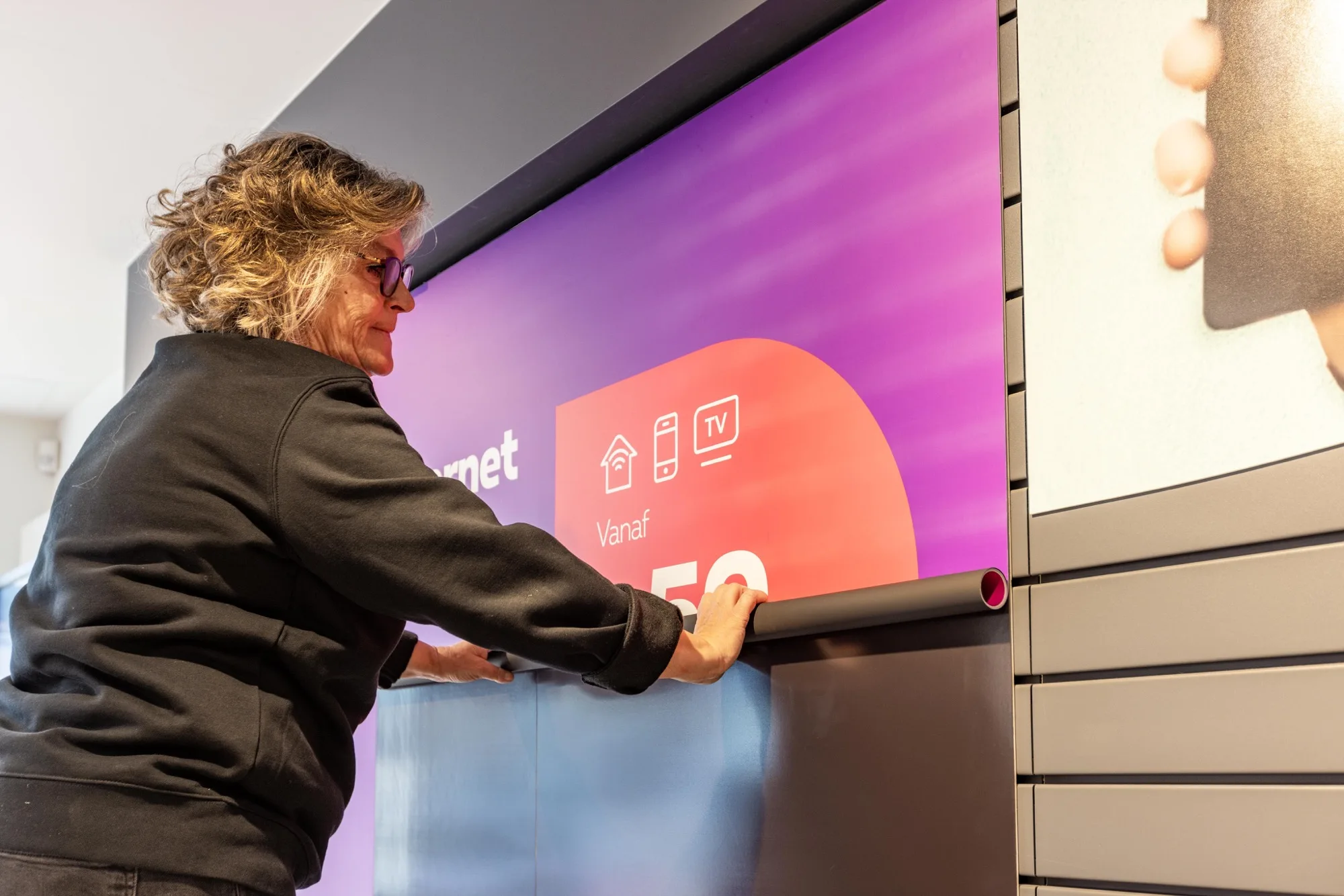 Field & Concept merchandiser applying an internet promotion wall graphic in a Proximus store