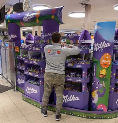 Field & Concept merchandiser restocking a Milka chocolate display stand in-store