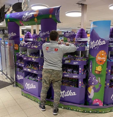 Field & Concept merchandiser restocking a Milka chocolate display stand in-store