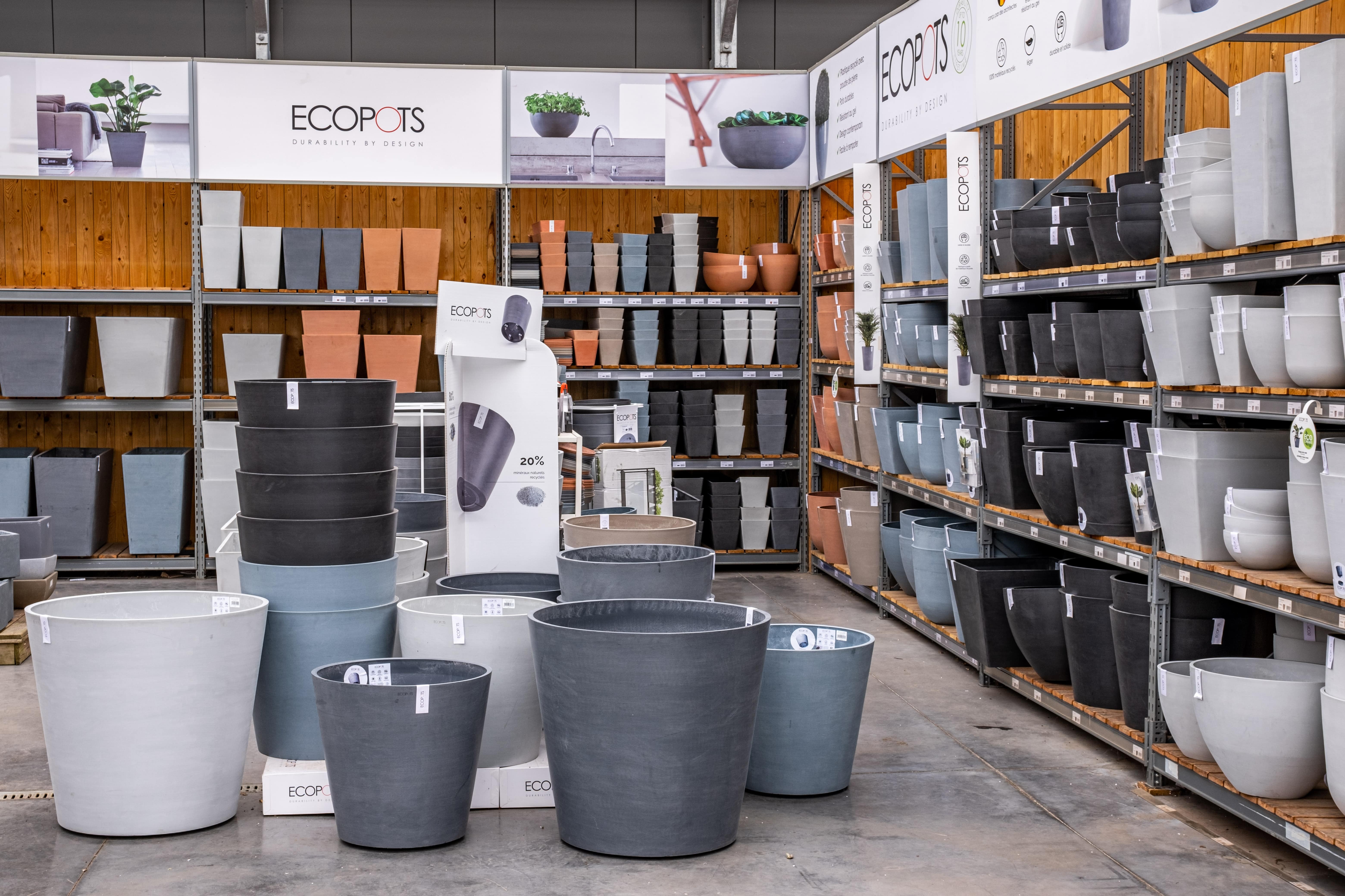 Ecopots planter display with rows of grey, terracotta, and blue pots on shelving and the warehouse floor, part of a Field & Concept merchandising project
