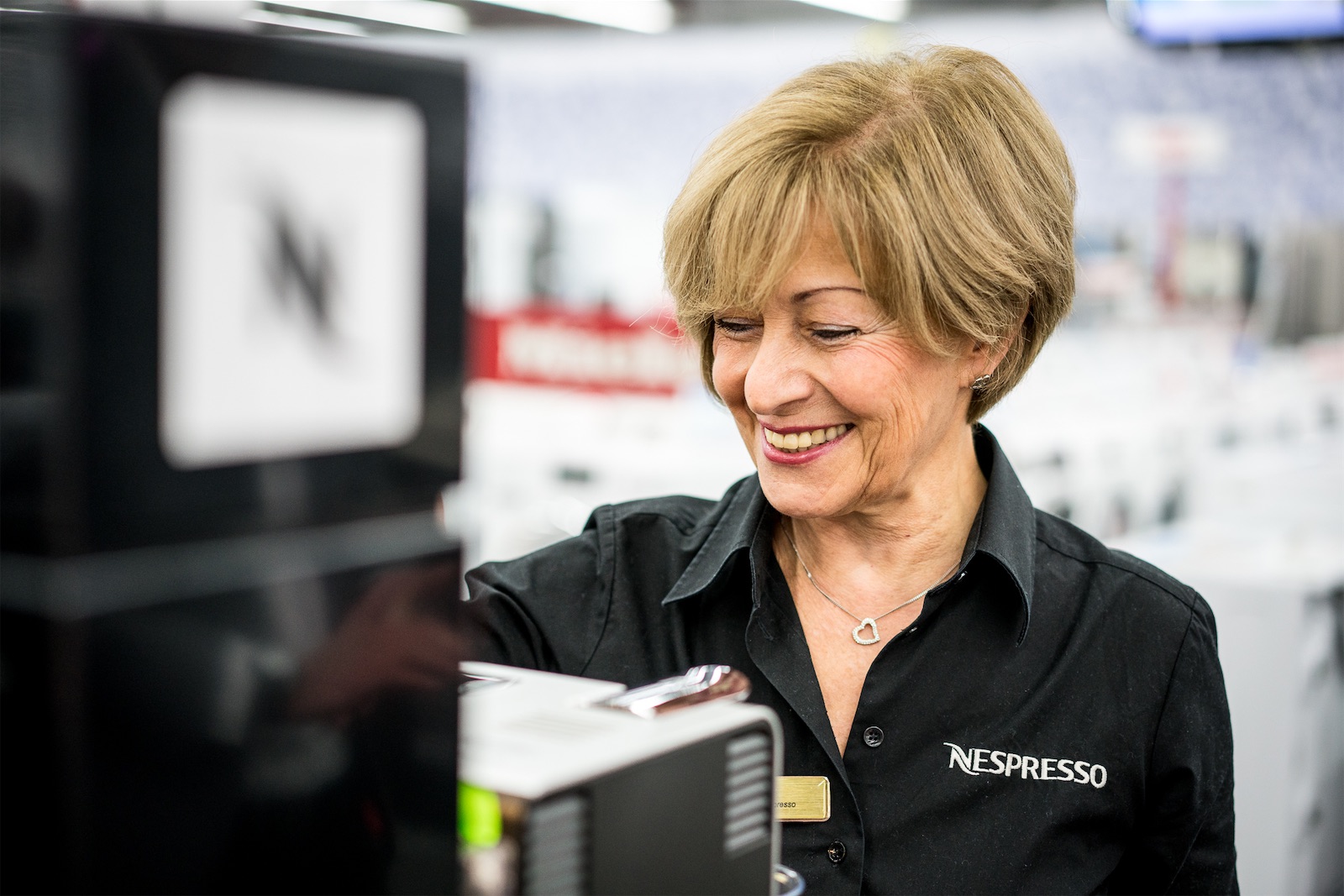 Field & Concept Nespresso brand ambassador demonstrating a coffee machine at an in-store promotional stand
