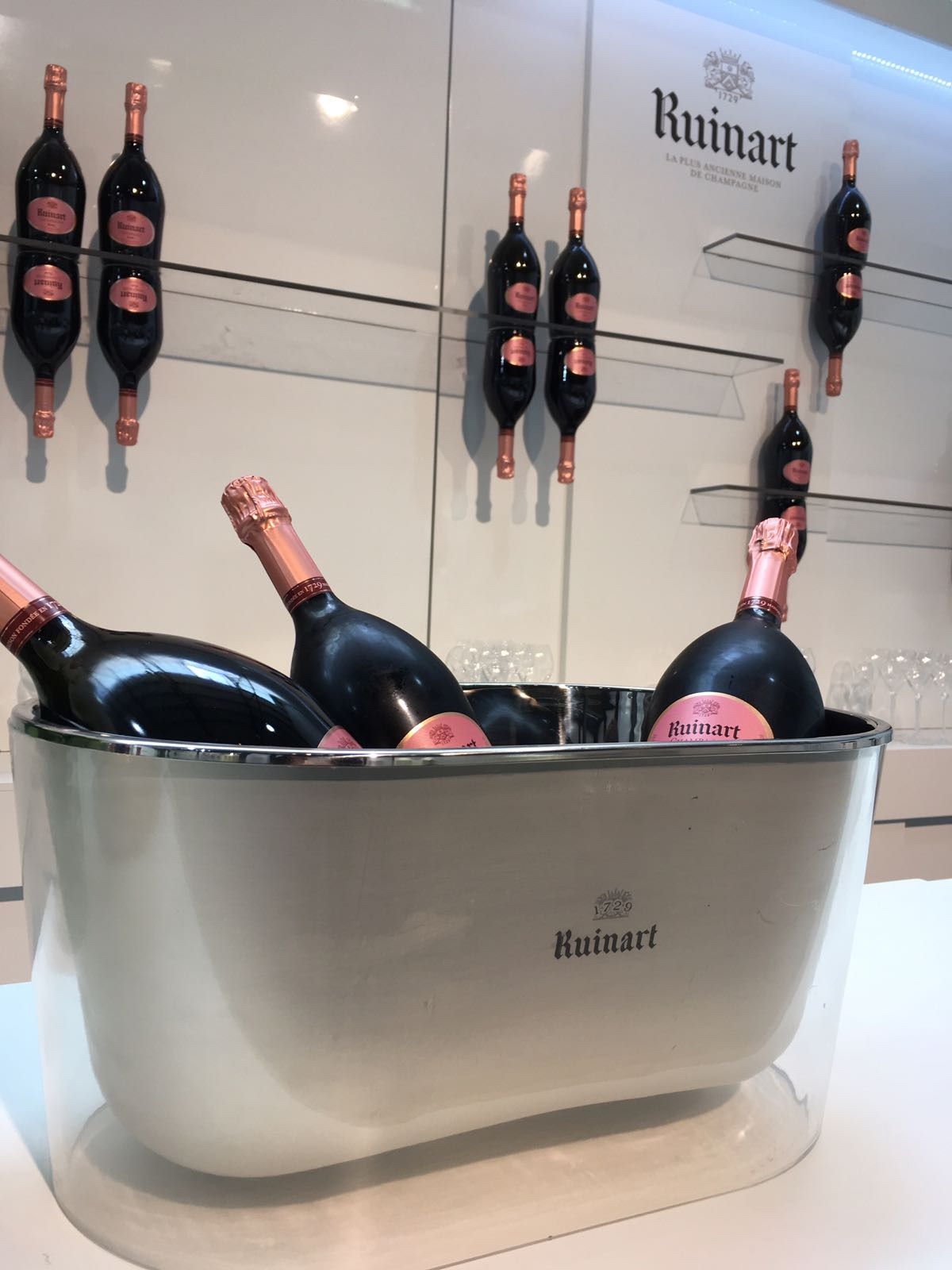 Ruinart champagne bottles displayed in a chilled metal ice bucket and wall-mounted rack for a Field & Concept retail activation