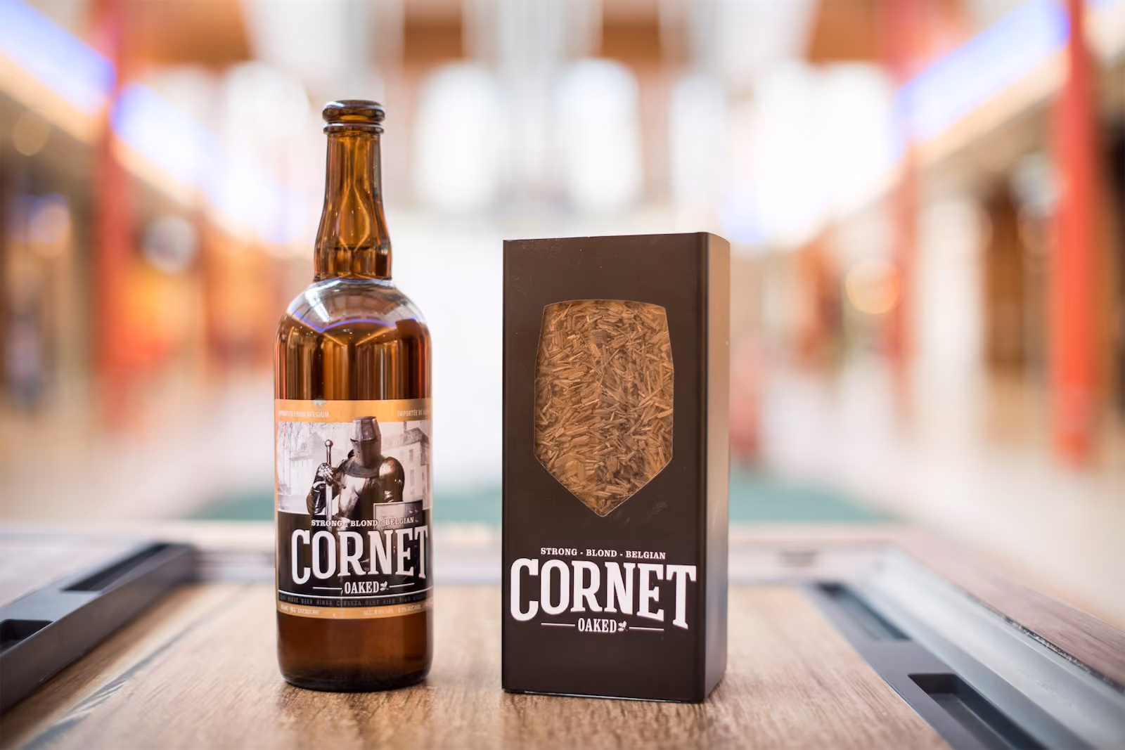 Bottle and gift box of Cornet Oaked strong Belgian blond beer displayed in a shopping mall, part of a Field & Concept retail activation