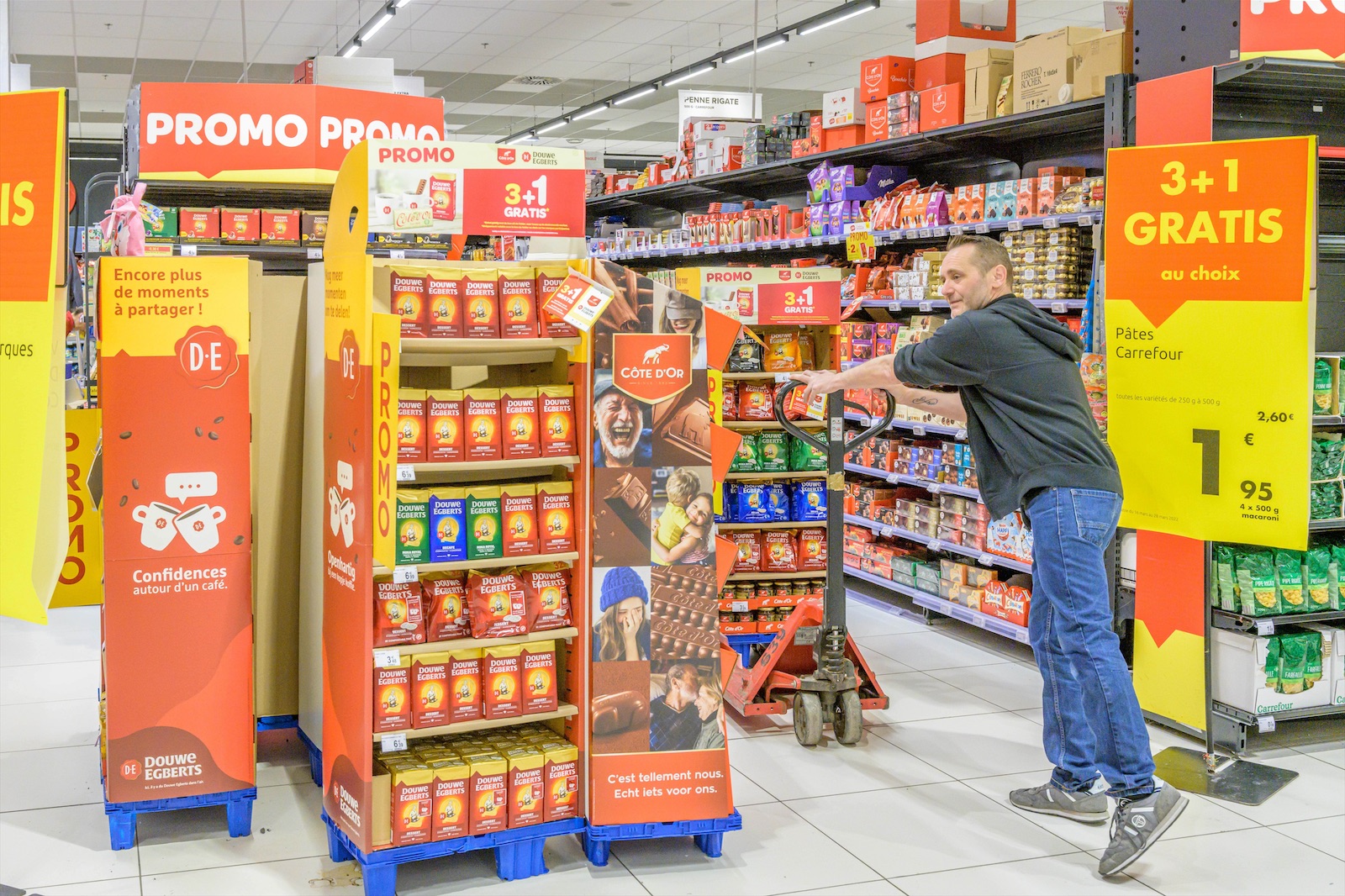 Field & Concept merchandiser setting up a Douwe Egberts and Cote d'Or promotional 3+1 free display in a supermarket aisle