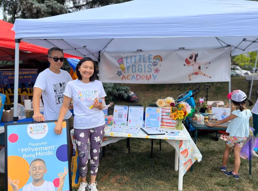 People at a Busy Minds Franchise booth, smiling for a photo