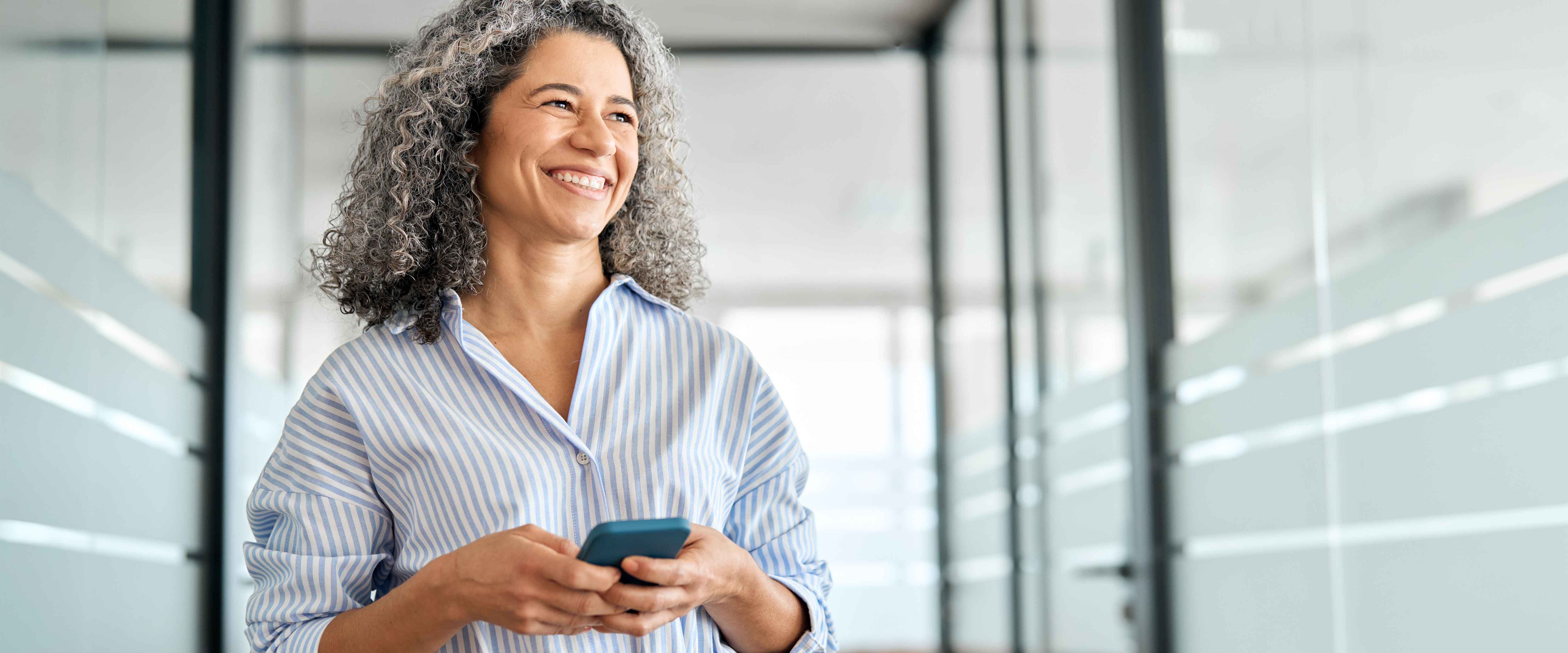Professional woman smiling while holding phone