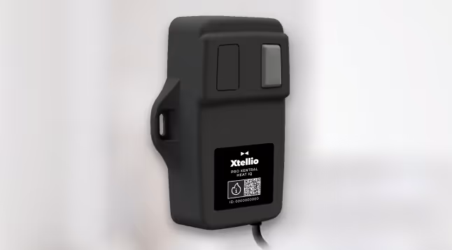 An Xtellio Pro Xentral Heat IQ device placed on a table in a blurred and bright environment