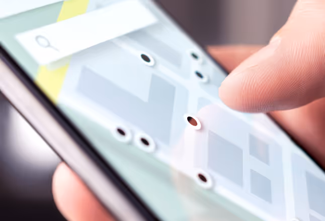 A photo of a hand holding a mobile phone displaying a map with multiple location pins.