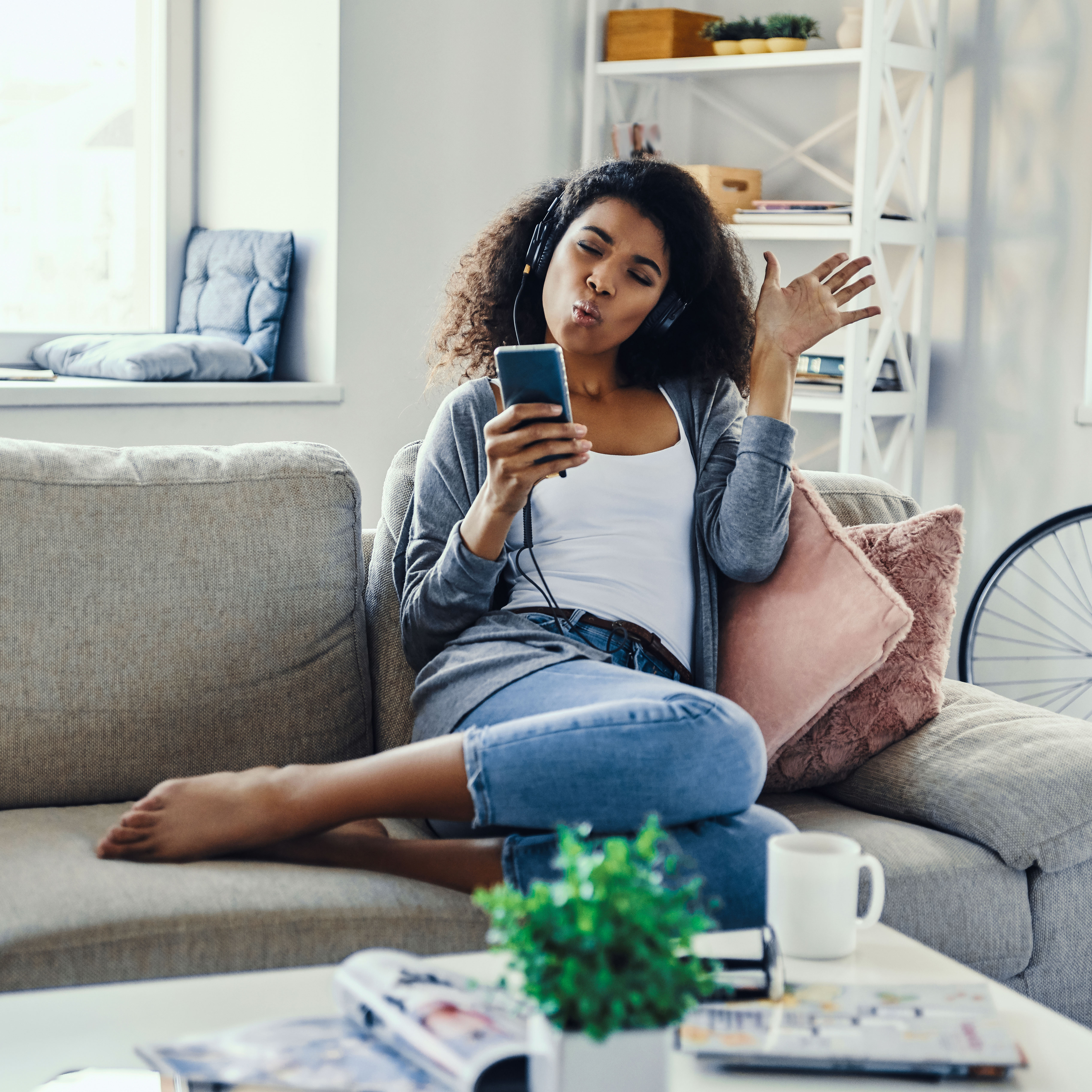 A woman sitting on a sofa enjoying music on her phone