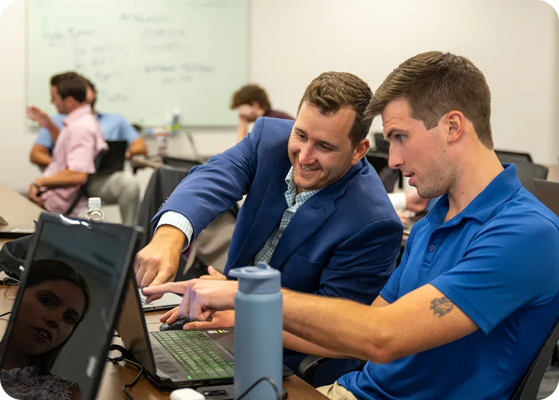 Two men discussing in front of laptop