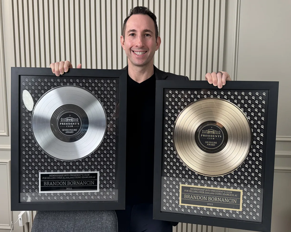 Brandon Bornancin holding up the six and seven figure President's Club awards.