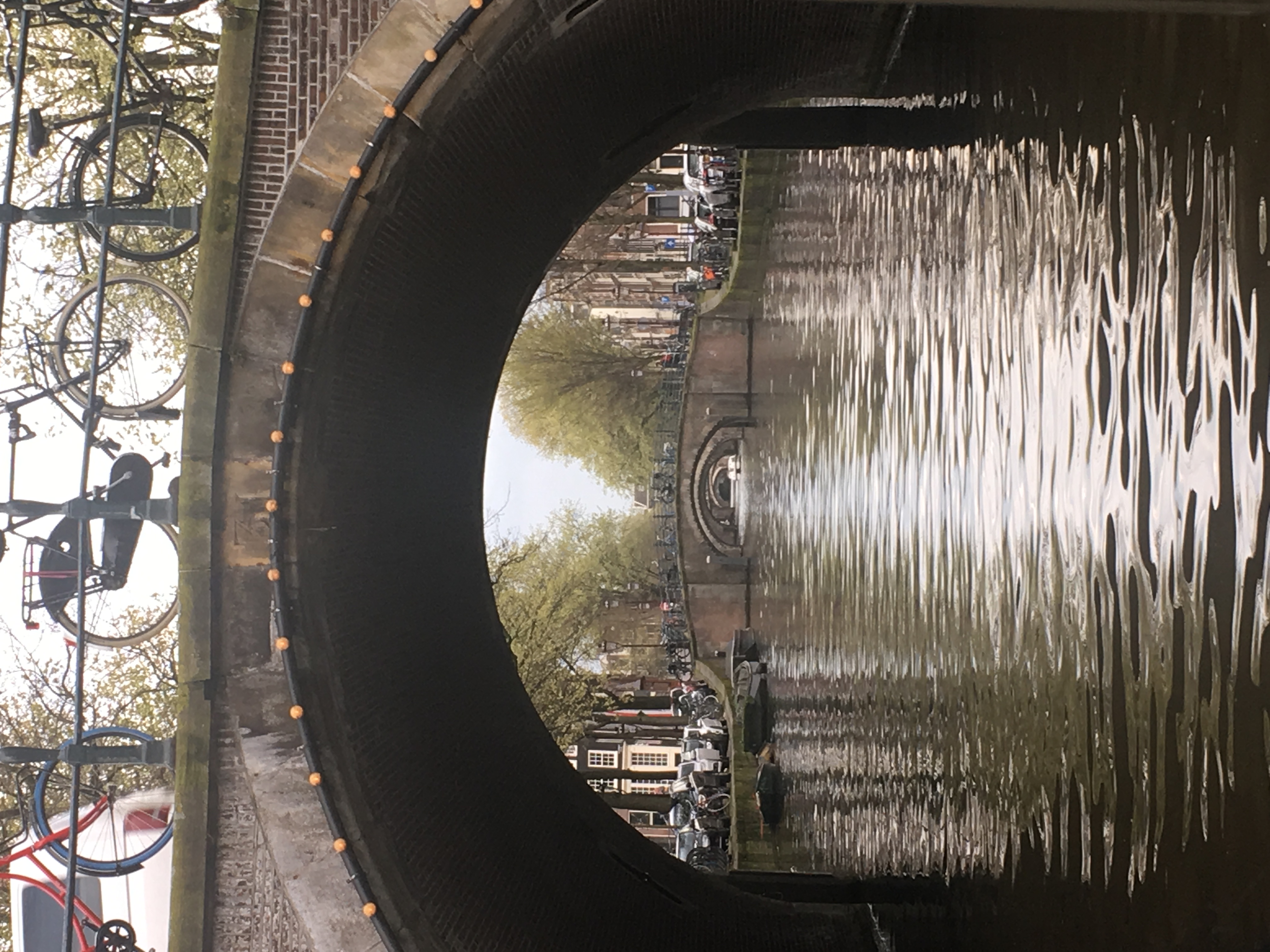 A quiet Amsterdam canal seen through the arch of a historic bridge