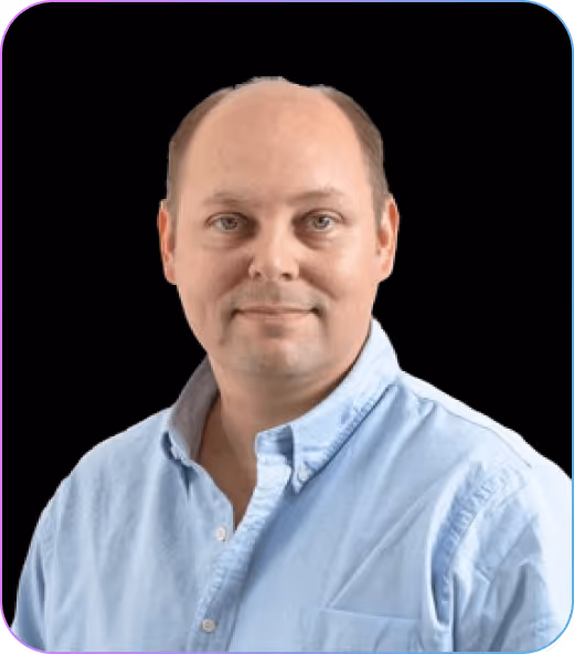 Portrait of a man with short hair wearing a light blue button-up shirt against a black background.